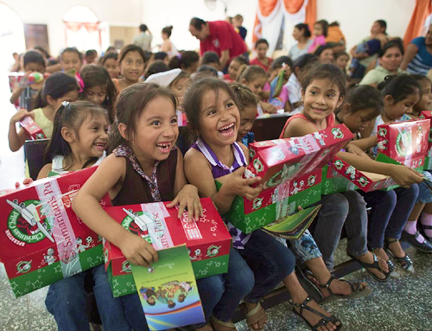 "Children smiling and holding gift bags during a Community Day celebration.