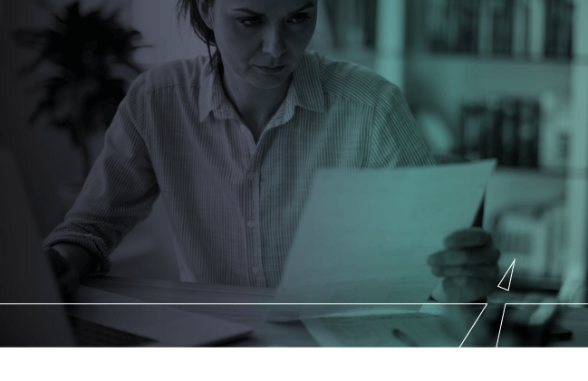 A woman reads a report at her desk